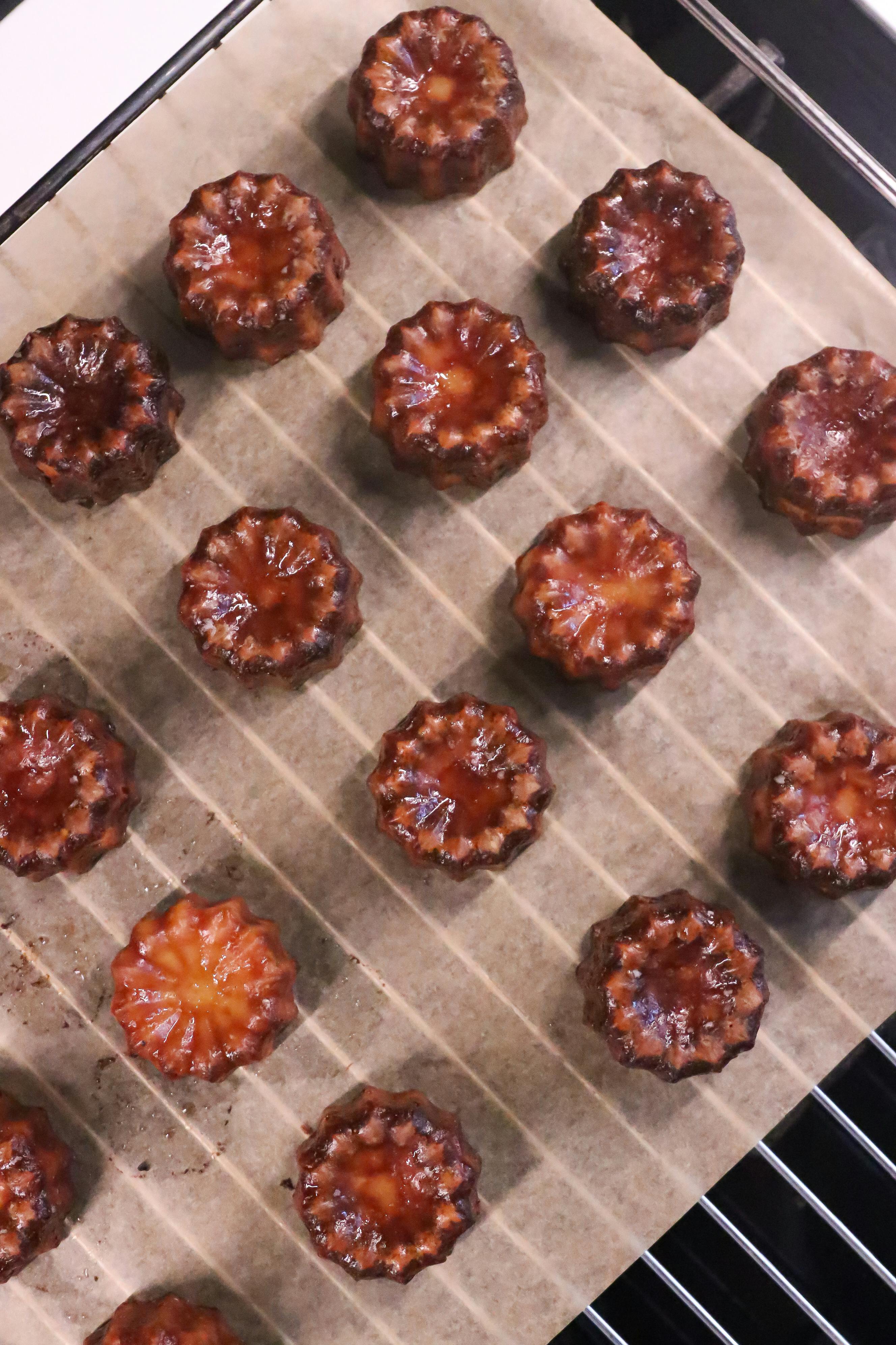 Top-down view of canelés on parchment in a grid formation
